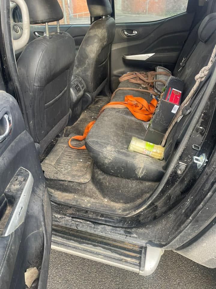 Banquette arrière d'un pick-up avant nettoyage, tapis couverts de boue et d'outils